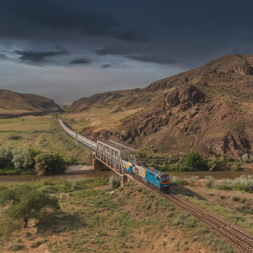 тепловоз тэп33а с пассажирским поездом тальго talgo на фоне гор лето казахстан ктж мост река